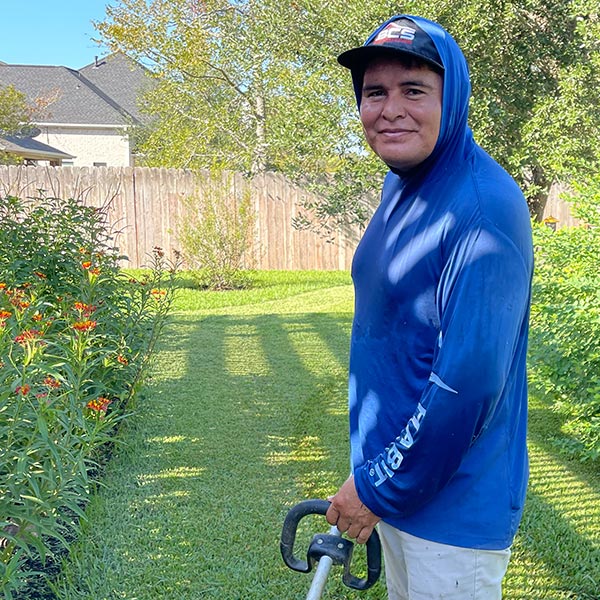 Jose Gamez working with a string edger next to a flowerbed